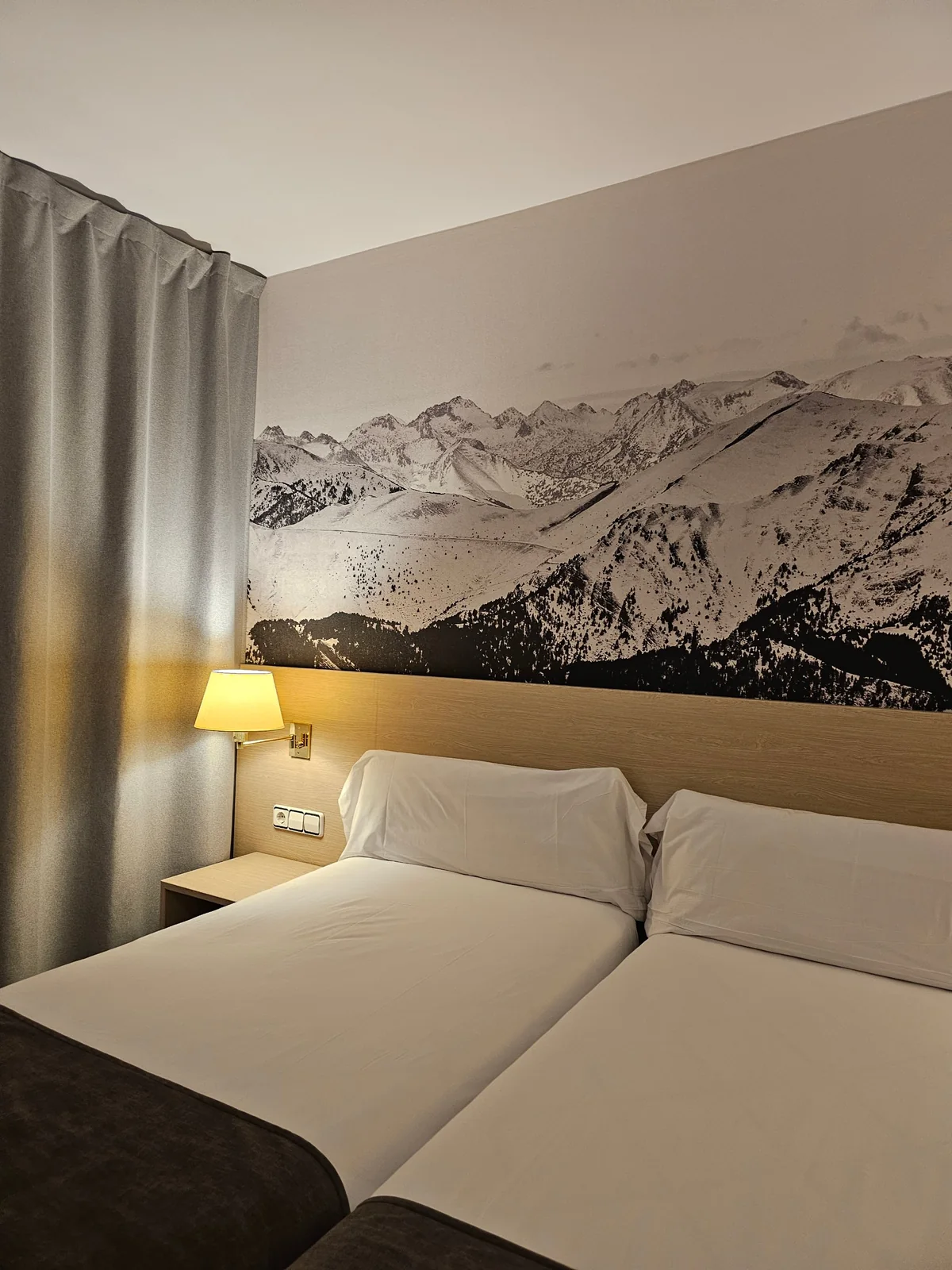Cabecero de habitación con mural de montañas y aplique