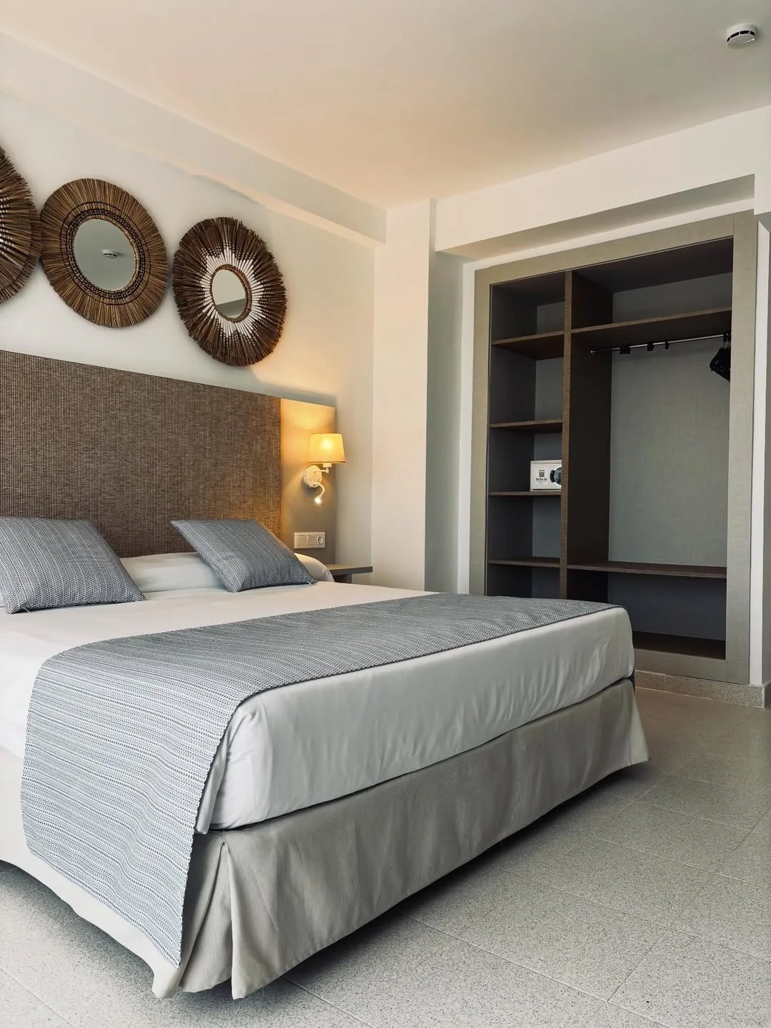 Habitación de hotel con cabecero revestido y espejos redondos