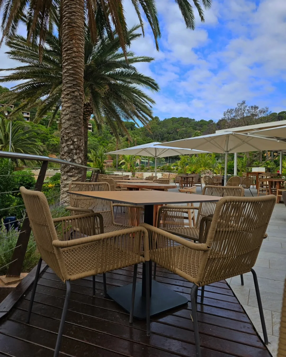 Terraza del hotel Meliá de Tossa de Mar con mesas, sillas y palmeras